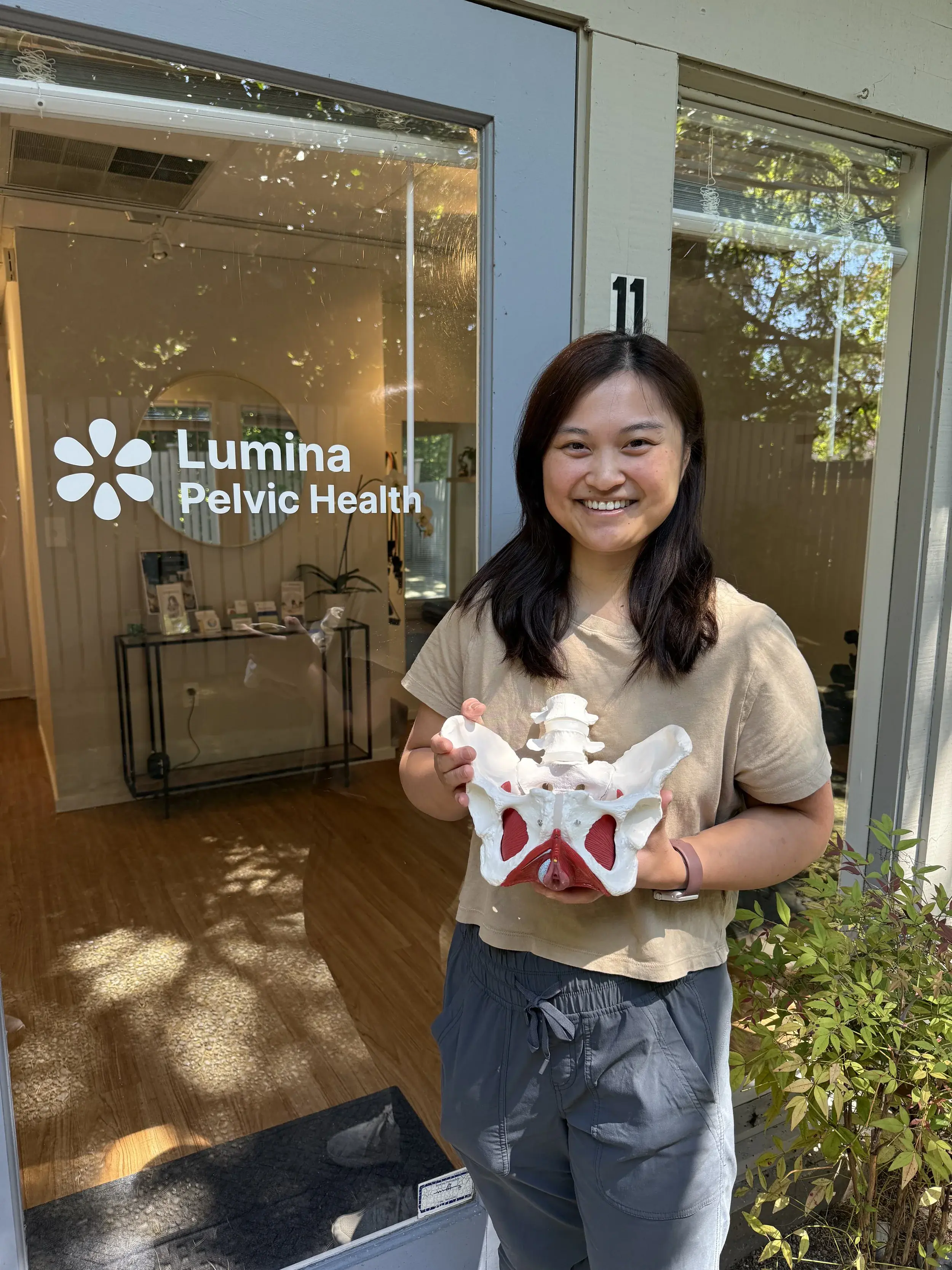 Meilin holding a pelvic model in front of Lumina Pelvic Health clinic